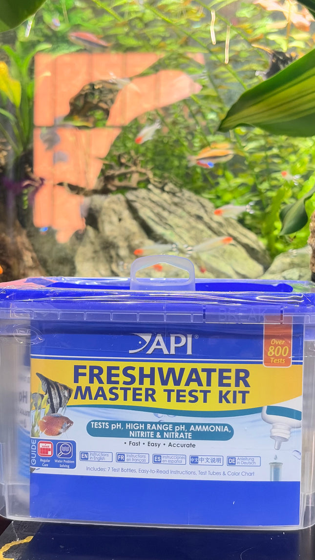 API Freshwater Master Test Kit in a clear plastic storage box with a blue lid and blue label, set against a blurred aquarium background.